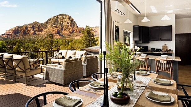 A modern kitchen with dark cabinetry, a large island, and a dining area with a view of a mountainous landscape. - Roca Roja by Avantstay Mountain Views in the Heart of Sedona (Sedona)
