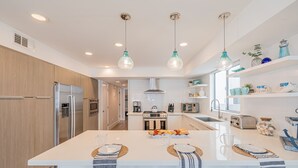 A modern kitchen with a central island, stainless steel appliances, and pendant lighting. - Seaside Style by Avantstay Rooftop Walk to Beach Chic Design (Newport Beach)