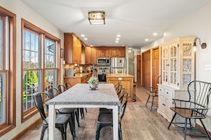 A kitchen with wooden cabinets, a central island, and a dining area with chairs.
