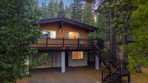 Une cabane avec une façade en bois, un balcon et un escalier menant à l’entrée.
