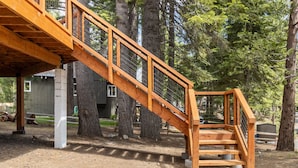 Un escalier en bois mène à un bâtiment doté de fondations en béton, qui est entouré d’arbres.