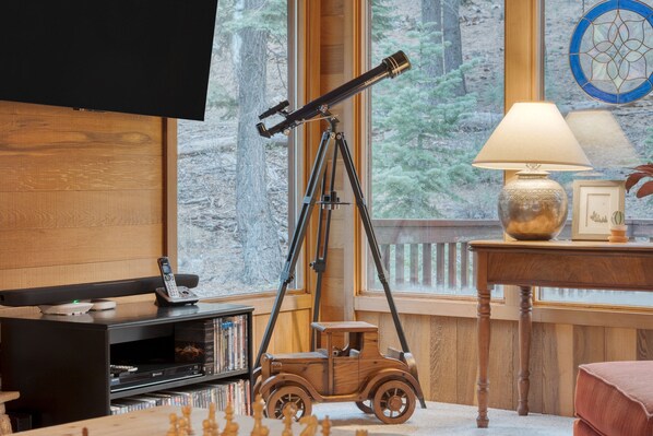 A room with a telescope, a wooden toy car, a lamp, and a bookshelf.