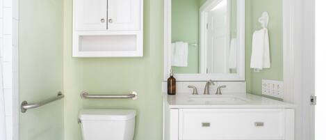 A bathroom with a toilet, a sink, a mirror, and a cabinet.