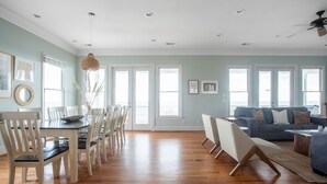 A spacious living area with a dining table and chairs, a sofa, and a ceiling fan. - Poseidon By Avantstay On The Beach Two Ocean Facing Balconies Hot Tub (Folly Beach)