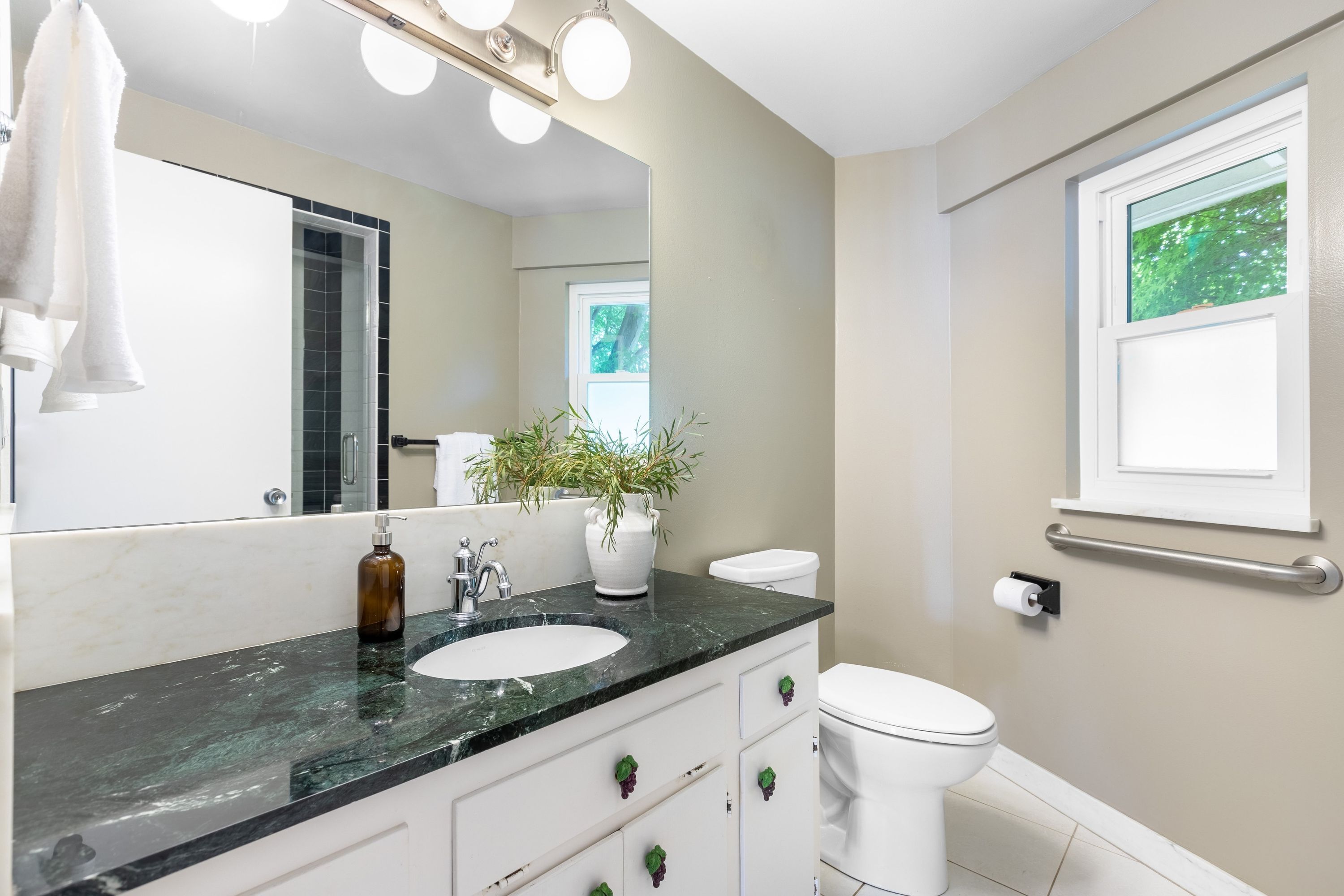 A bathroom with a white sink, a mirror, a toilet, and a window.