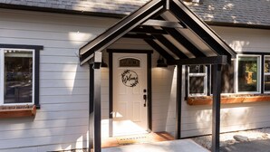 Una casa con fachada blanca, techo negro y una puerta acogedora con un letrero que dice 'Welcome'.