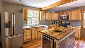 Una cocina con gabinetes de madera, electrodomésticos de acero inoxidable y una isla central.
