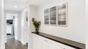 A hallway with white cabinetry and a dark countertop, leading to a kitchen area. - Shelly by Avantstay Steps to the Beach Deck w Ocean Views 5bdr (Newport Beach)