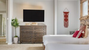 Ein Schlafzimmer mit Bett, Schminktisch, Fernseher und einer Wanddekoration aus Makramee.