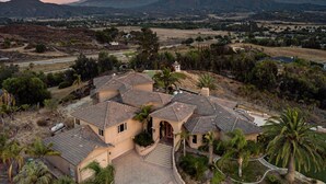 A large, multi-story house with a spacious driveway and a well-maintained garden.