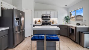 A modern kitchen with stainless steel appliances, a central island, and bar stools. - Pacifica Sur by Avantstay Pool Hot Tub Gazebo (Indio)