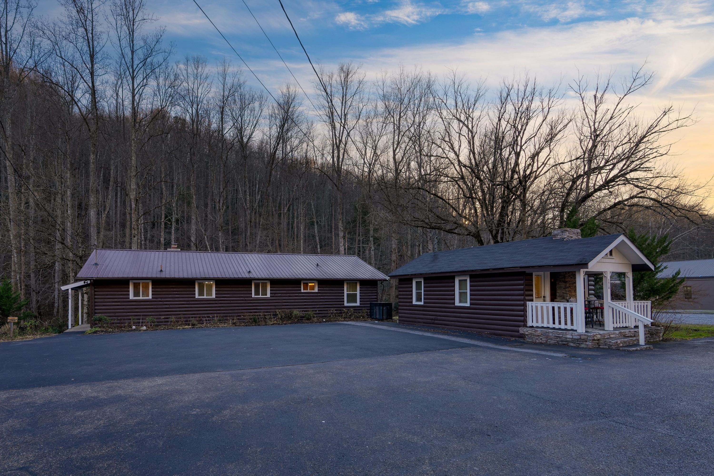 A two-story log cabin with a porch and a small attached structure.