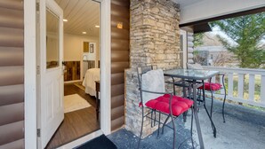 A covered outdoor area with a stone fireplace, a glass table, and red cushioned chairs. - Creekside Haven Gatlinburg Escape by a Bubbling Creek Near Top Attractions (Gatlinburg)