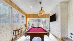 A pool table in a room with wooden walls, large windows, and a mounted TV. - Creekside Haven Gatlinburg Escape by a Bubbling Creek Near Top Attractions (Gatlinburg)