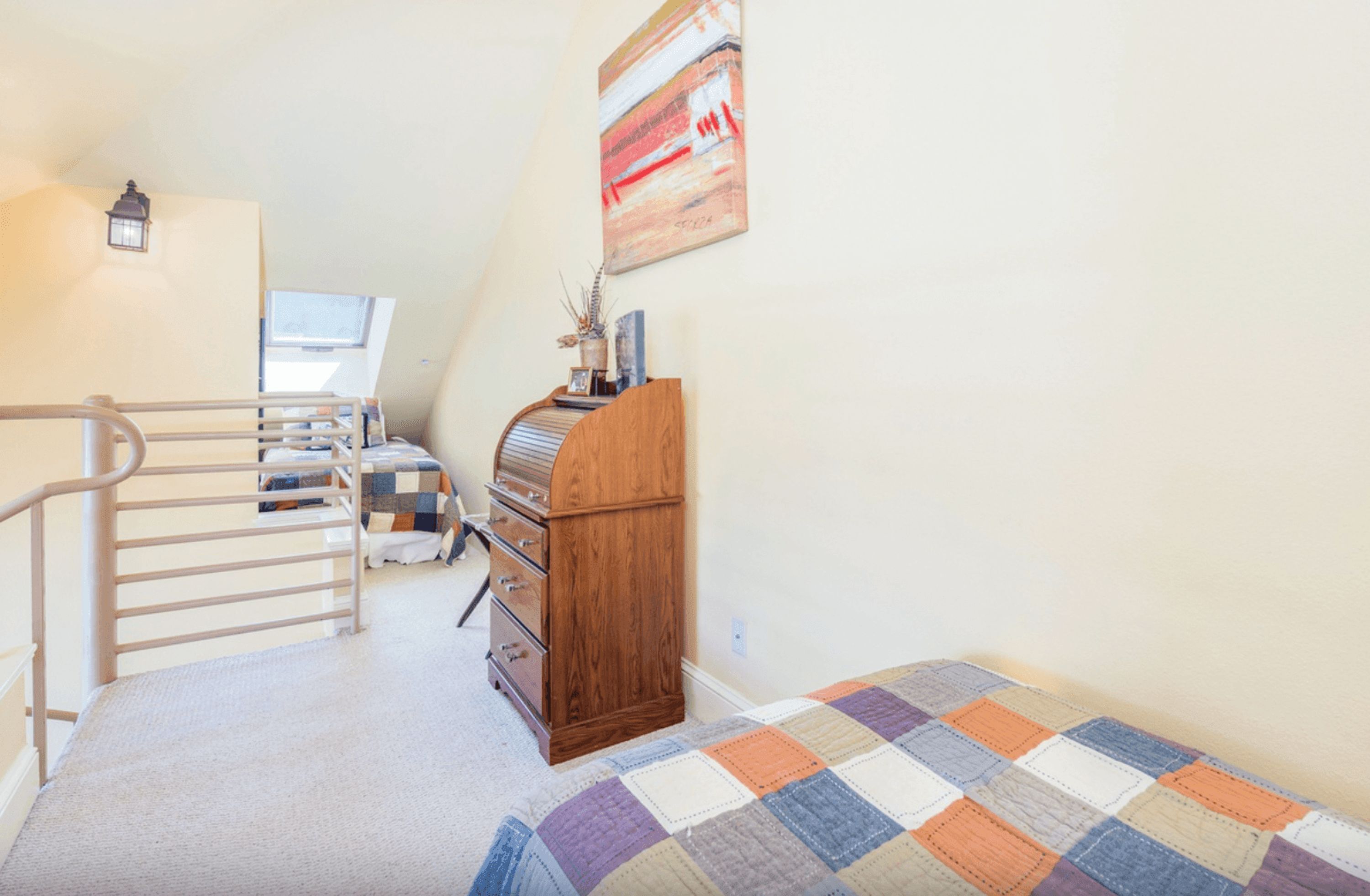 A bedroom with a bed, a dresser, a nightstand, a lamp, a window, and a painting on the wall.