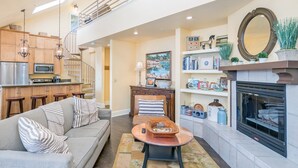 A modern living room with a sofa, coffee table, and fireplace. There is a kitchen area with a microwave and refrigerator. - Blue Mesa Penthouse by Avantstay Buyout of 3 Units Ski-in Ski-out Condo (Telluride)