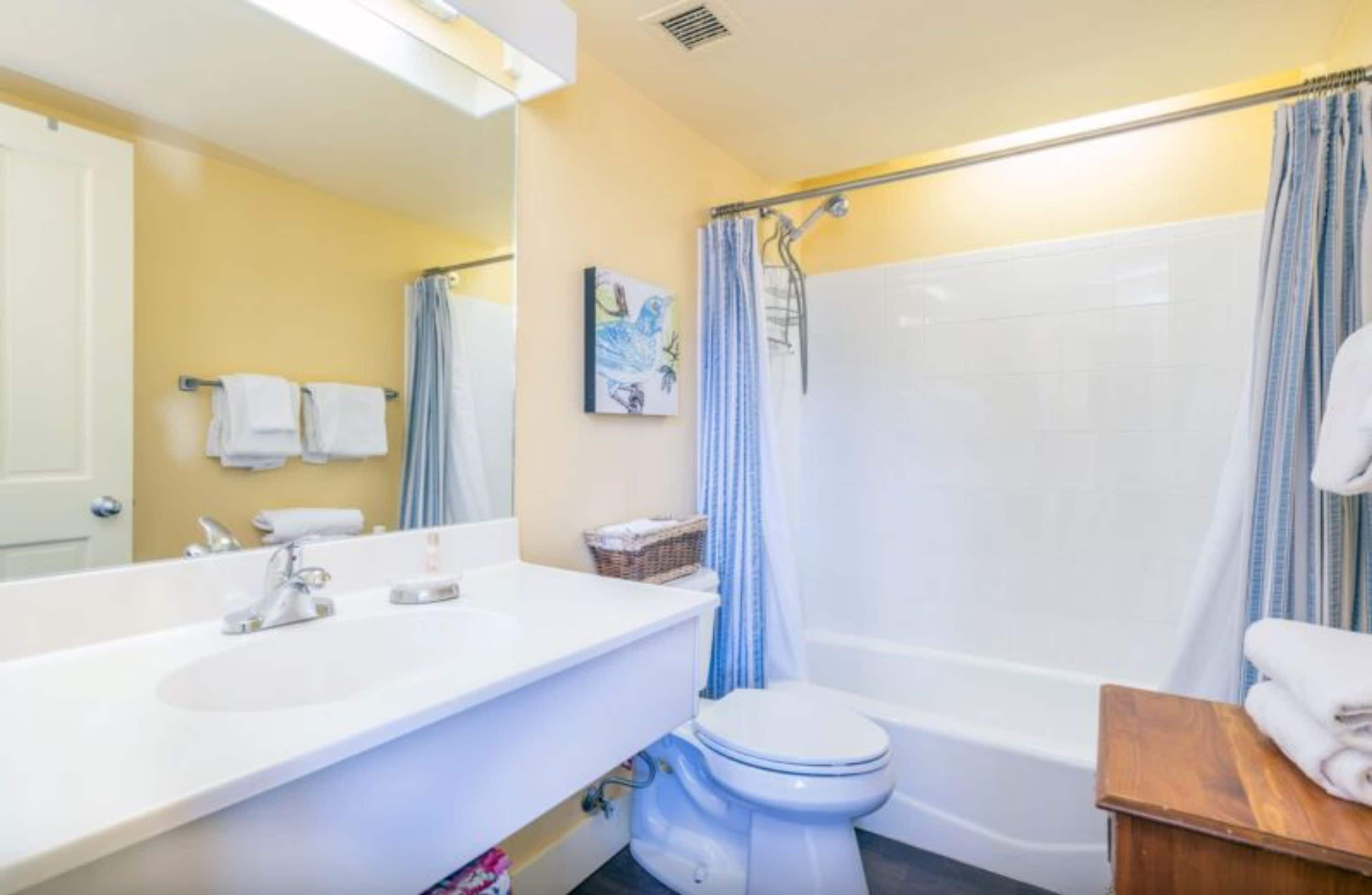 Une salle de bain avec un lavabo blanc, des toilettes et une baignoire.