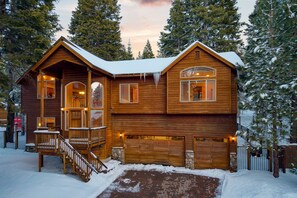A wooden cabin with a balcony, a garage, and a brick driveway. - Cherry Hills Spacious Tahoe Cabin With Deck Fireplace Open Interiors (South Lake Tahoe)