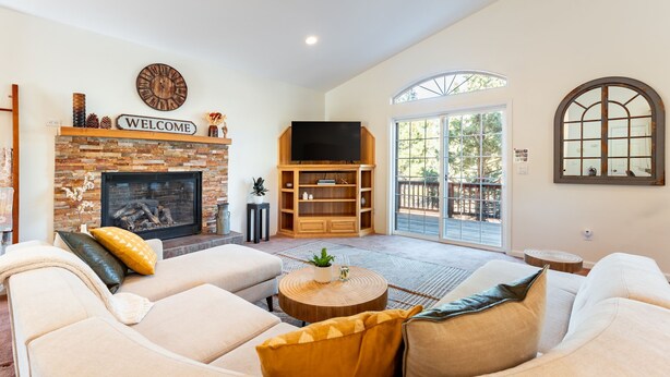 A spacious living room with a fireplace, a television, and a large window. - Blitzen by Avantstay Pet-friendly Tahoe Retreat (South Lake Tahoe)