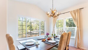 A dining area with a wooden table set for four, surrounded by cushioned chairs. - Blitzen by Avantstay Pet-friendly Tahoe Retreat (South Lake Tahoe)