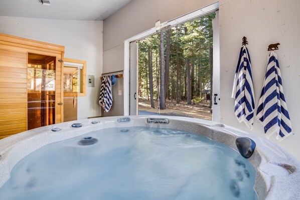 A hot tub with a view of a forest through an open door. - Homewood by Avantstay Amazing Family Cabin w Hot Tub Sauna (Homewood)