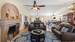 A spacious living room with a fireplace, leather sofas, a coffee table, and a patterned rug. - Chardonnay Charm by Avantstay Luxe Group Retreat w Pool Mins to Wineries (Temecula)