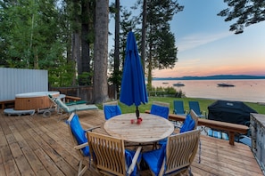 A wooden deck with a round table and chairs, overlooking a lake with boats. - Lakefront Haven by Avantstay Minutes to Ski Resorts Private Dock Boat (Homewood)