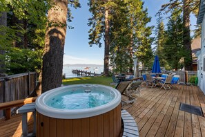 A wooden deck with a hot tub, outdoor furniture, and a view of the water. - Lakefront Haven by Avantstay Minutes to Ski Resorts Private Dock Boat (Homewood)