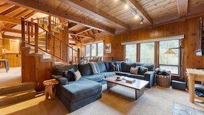 A spacious living room with a large sectional sofa, a coffee table, and a wooden staircase.