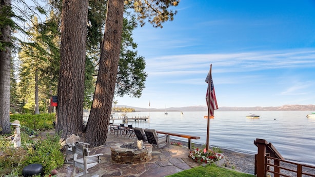 Eine Terrassensitzgelegenheit am Seeufer mit Steinsitzmöbeln, einer Feuerstelle und einer US-amerikanischen Flagge.
