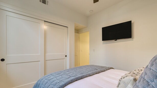 Una camera da letto con un letto, una TV a muro e una porta.