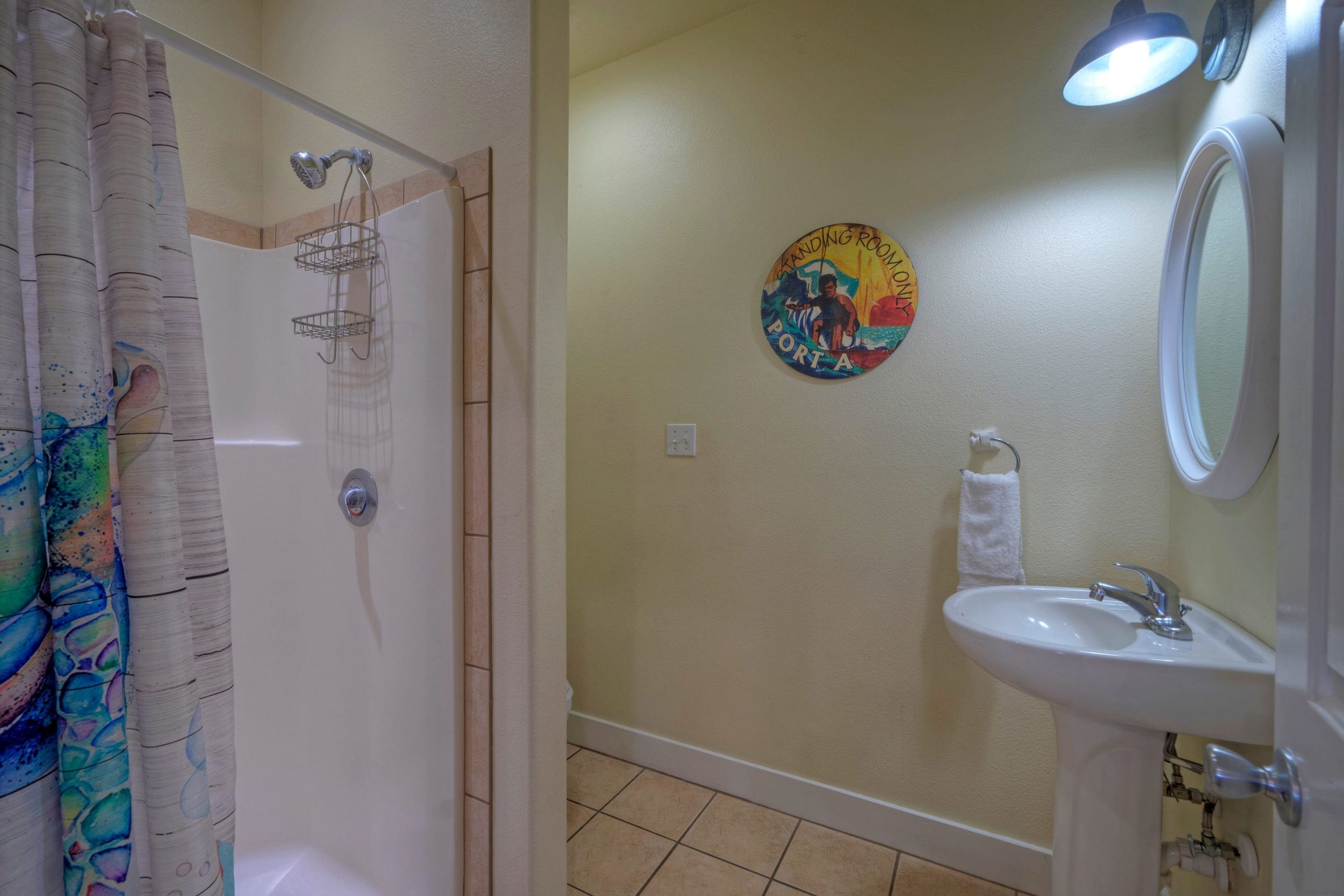 A bathroom with a shower, a sink, and a towel rack.