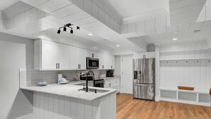 A modern kitchen with white cabinetry, stainless steel appliances, and a wooden floor. - Mizzenmast by Avantstay Harbourtown Escape Group Retreat w Patio (Hilton Head Island)