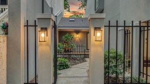 A gated entrance with a pathway leading to a covered area with a bench and potted plants. - Mizzenmast by Avantstay Harbourtown Escape Group Retreat w Patio (Hilton Head Island)