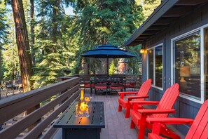 Un patio al aire libre con una chimenea, sillas Adirondack rojas y una mesa.