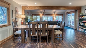 A dining area with a wooden table and chairs, a bookshelf, and a view of the outdoors. - Washoe Way by Avantstay Luxury Tahoe Retreat A Location w Beach Access (Tahoe City)