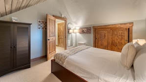 A bedroom with a bed, wooden wardrobe, and a mirror with wall-mounted lamps. - Washoe Way by Avantstay Luxury Tahoe Retreat A Location w Beach Access (Tahoe City)