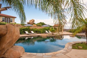 A swimming pool with lounge chairs and umbrellas, surrounded by rocks and greenery. - Colina by Avantstay Secluded Mountain Top Oasis w Pool Hot Tub Putting Green (Murrieta)