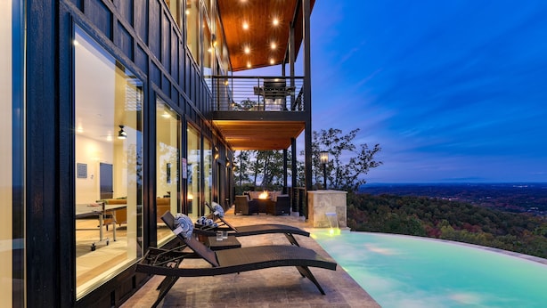 Une maison moderne dotée d’une piscine, de chaises longues et offrant une vue sur le paysage.