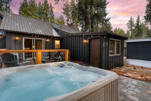Un bain à remous dans un jardin, avec une terrasse, une clôture en bois et un toit en métal.