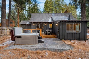 Une cabane dotée d’un bain à remous, d’un espace extérieur aménagé et d’une petite dépendance attenante avec une fenêtre.