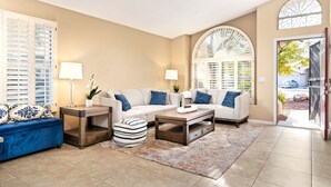 Un salon avec un mur beige, deux canapés, une table basse et un divan bleu.