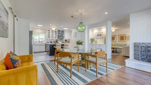 A modern kitchen with white cabinets, a dining area with a round table and chairs, and a living room with a yellow sofa. - Hummingbird Haven by Avantstay Dog-friendly Near the Beach Huge Yard Hot Tub (Santa Barbara)