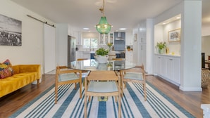 A modern kitchen with white cabinets, a glass dining table, and a green chandelier. - Hummingbird Haven by Avantstay Dog-friendly Near the Beach Huge Yard Hot Tub (Santa Barbara)