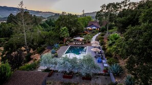 A pool area with a hot tub, surrounded by lush greenery and a deck with outdoor seating. - Kenwood Vista by Avantstay 7acres w Pool Fire Pit Vineyard Views (Kenwood)