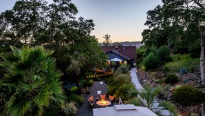 A backyard with a fire pit, outdoor seating, and a pathway leading to a house.