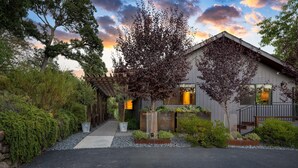 A modern house with a covered porch, a stone wall, and a well-maintained garden.