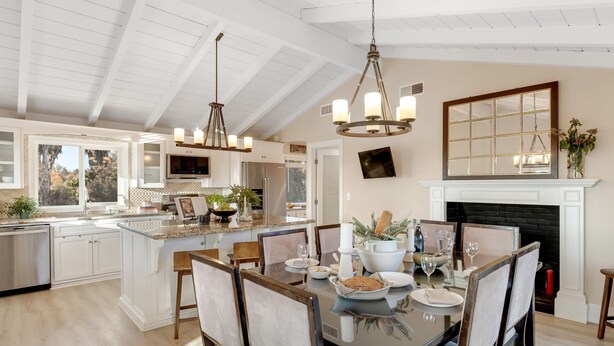 A spacious kitchen with white cabinetry, a central island, and a dining area with a large table and chairs.