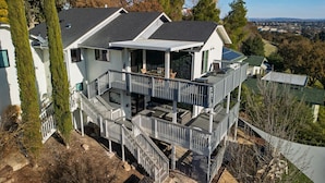 Ein mehrstöckiges Haus mit Balkon, Treppe und Blick auf die umliegende Landschaft.