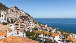 A coastal town with terracotta-roofed buildings, a clear view of the sea, and a hilly backdrop. - Camino De Flores by Avantstay Views Pool Beach Access Community Amenities (Avalon)